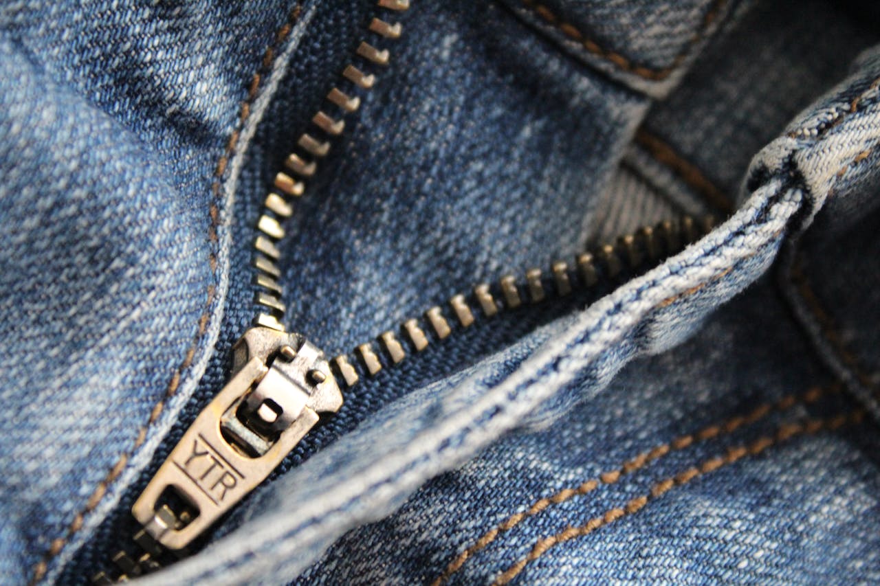 Detailed close-up of a blue jean zipper with visible YTR branding, showcasing denim texture.